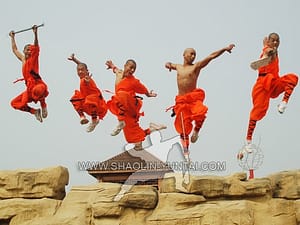 Shaolin-Monks jumping high with their weapons while training in the nature